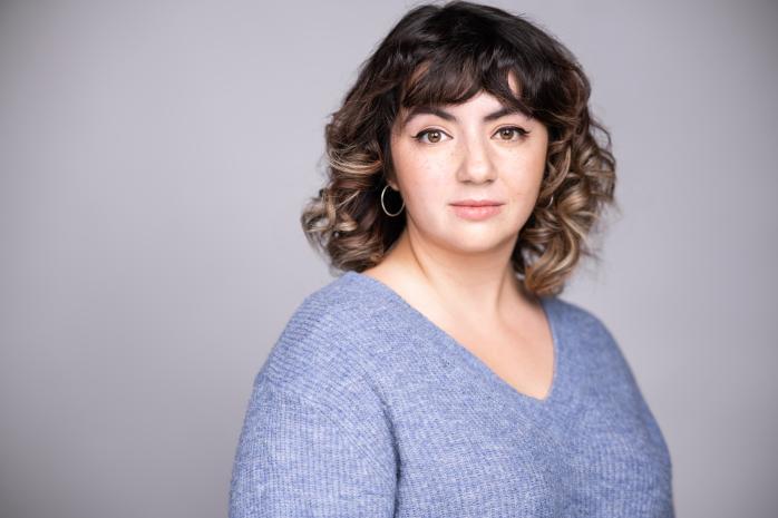 Aisling Murphy in a blue shirt in front of a grey background. 