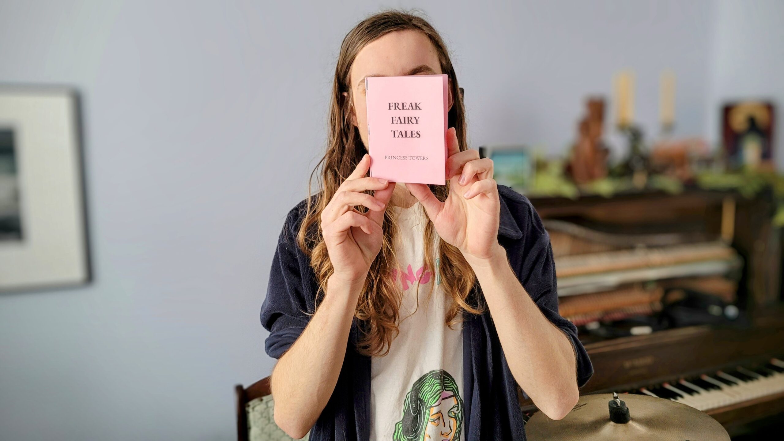 Photo of Arden Rogalsky holding their pink book titled, 'FREAK FAIRY TALES.'