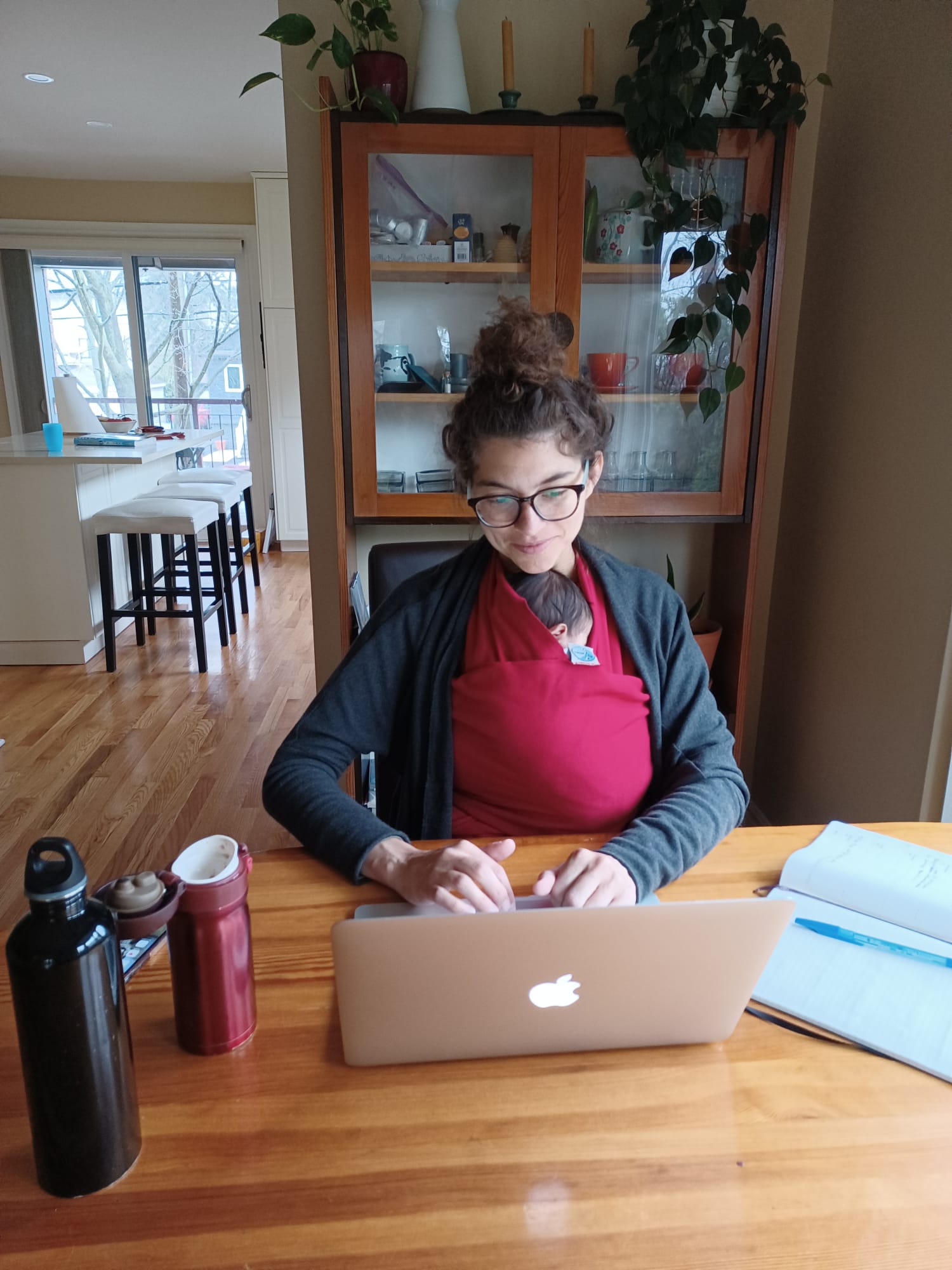 Photo of Sarah Waisvisz typing on her laptop while holding a baby.