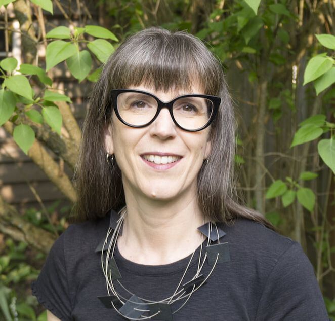 Photo of Dr. Jenn Stephenson. She wears glasses with a black shirt and the background is a leafy tree.