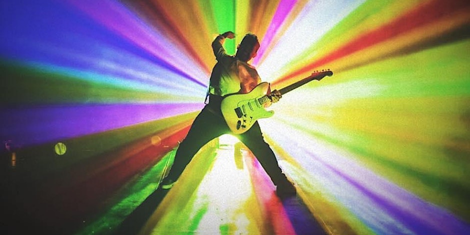 Someone plays the guitar and rainbow beams expel from the person.