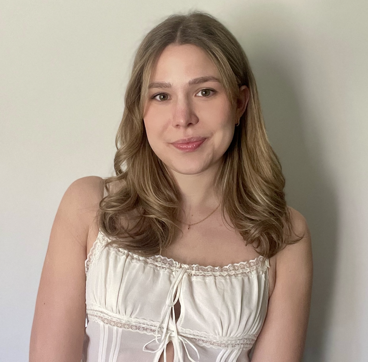 Headshot of Charlie Hensel. She is in front of a plain wall and wears a white tank top. 