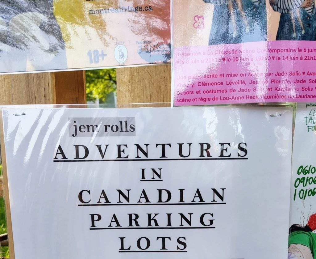a white paper sign with black text reading: "ADVENTURES IN CANADIAN PARKING LOTS"