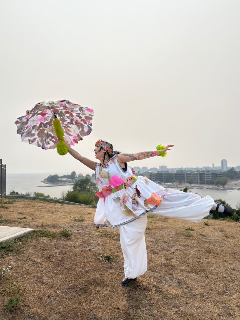 A woman posing with a colourfully decorated umbrella. 