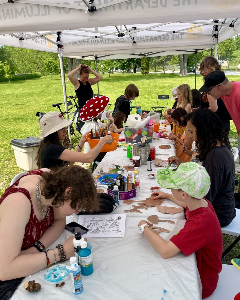 A group of people crafting at a table outside. 