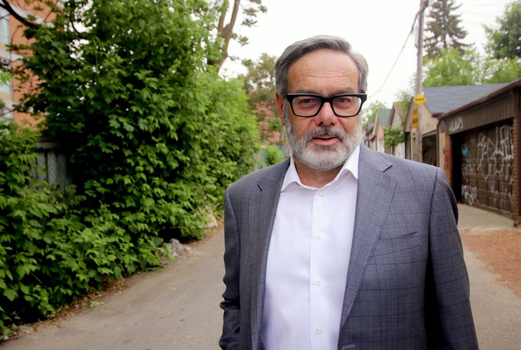 A white man with a beard and glasses wearing a suit.
