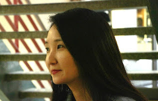 Headshot of Jung-Ah Kim. There is a staircase in the background and the photo is portrait-wise.