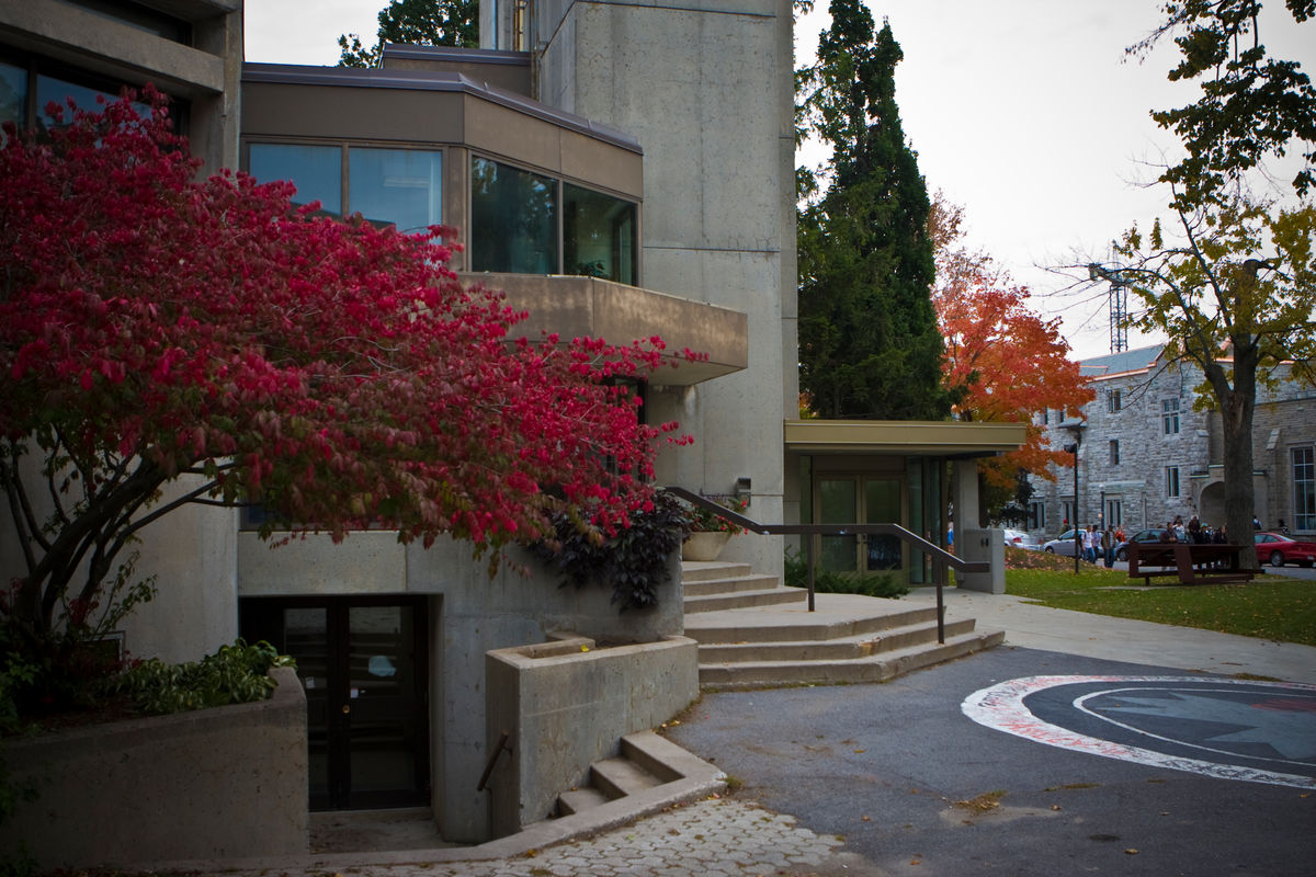 Concrete building with a red-leafed tree outside