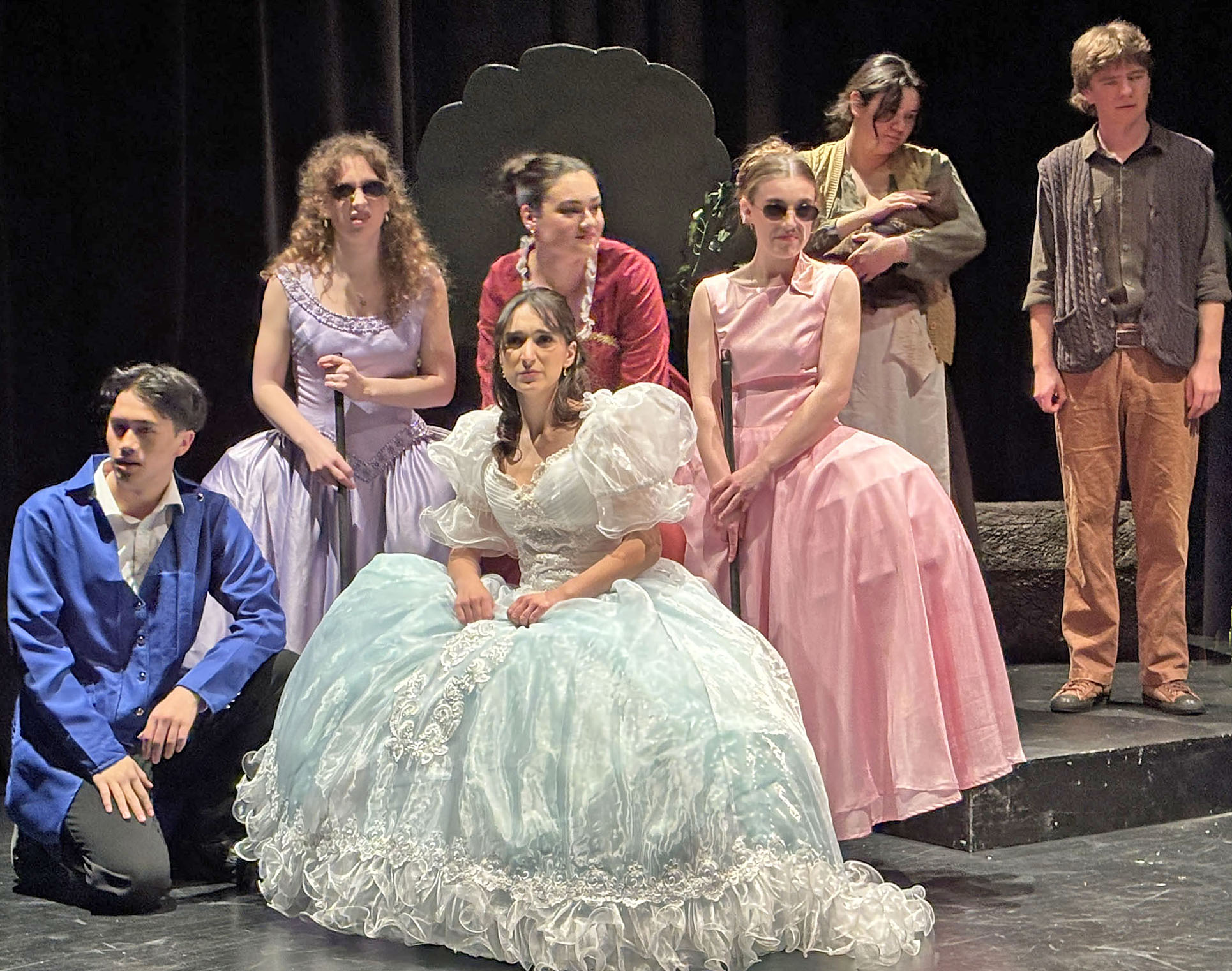 A group of performers on stage. They wear various costumes of storybook characters.