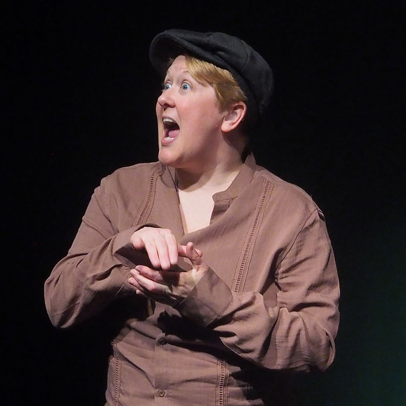 A performer has their hands clasped and looks absolutely thrilled. 