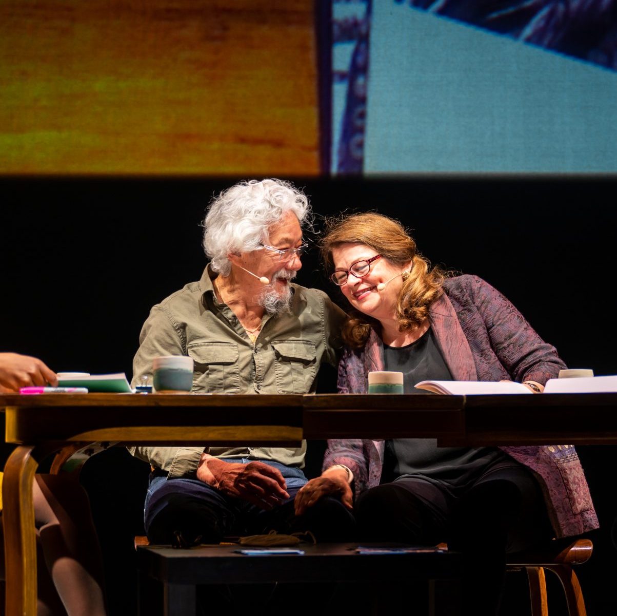 Four people sit in chairs around a kitchen table.