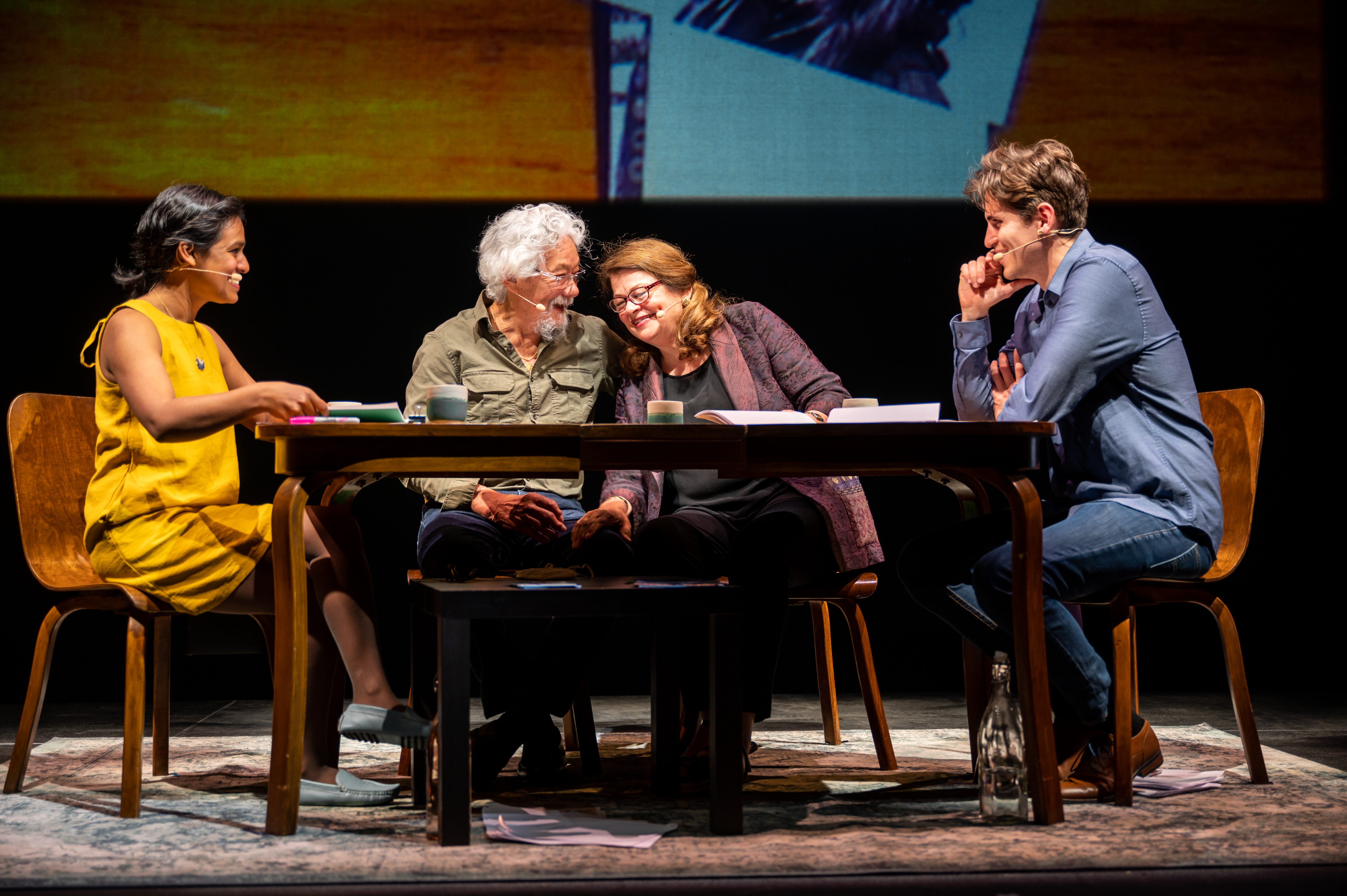 Four people sit in chairs around a kitchen table. 