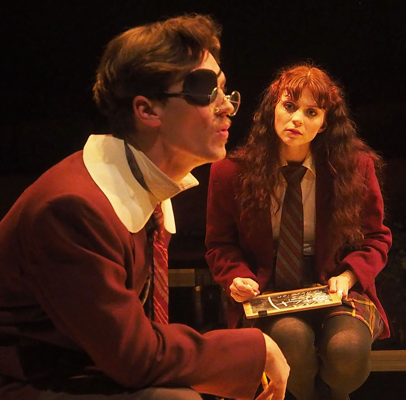 A man in an eyepatch stares off while a woman appears to write something day, paying much attention to what he is saying. 