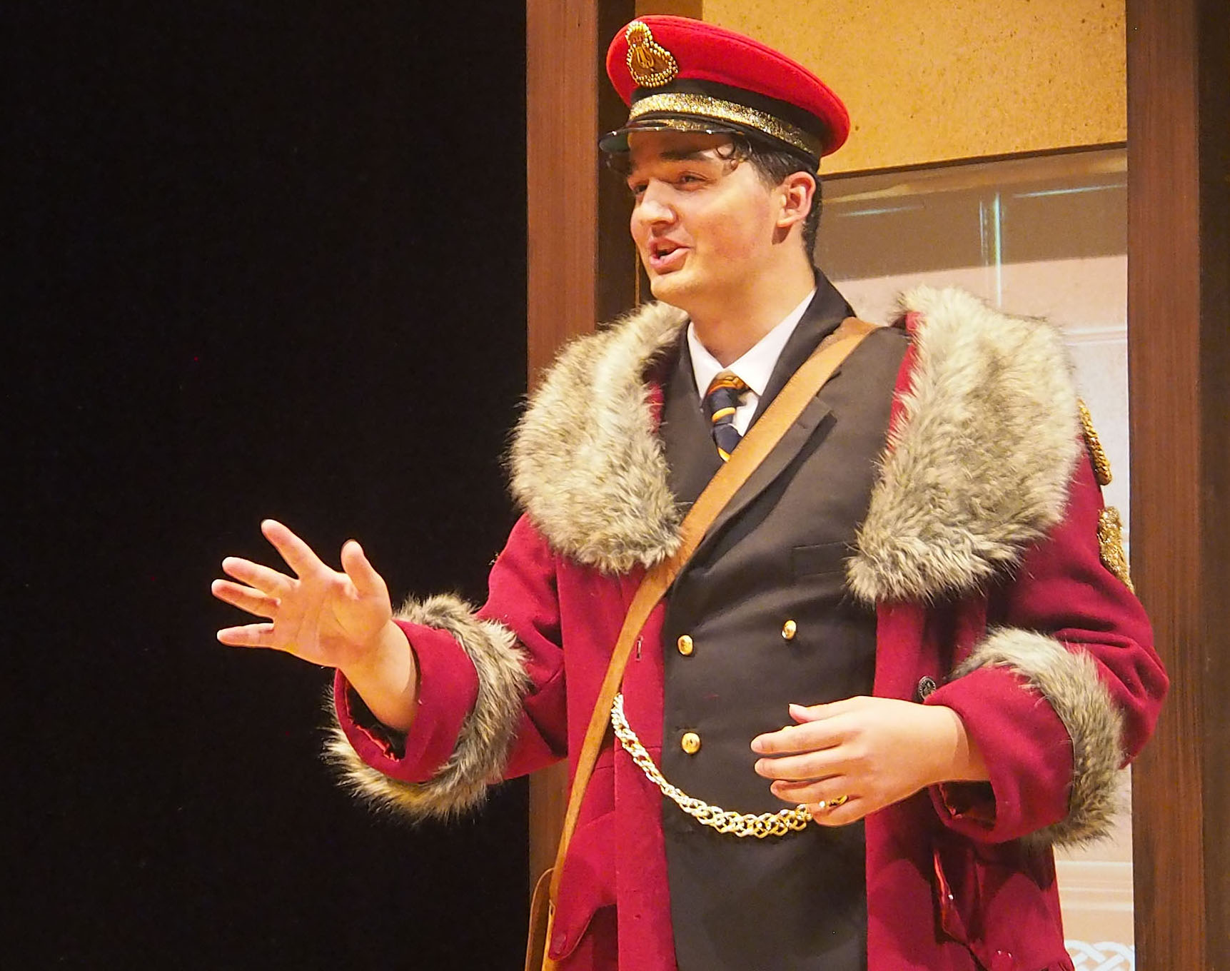 A man in uniform and fur coat addresses someone outside the frame of image. 