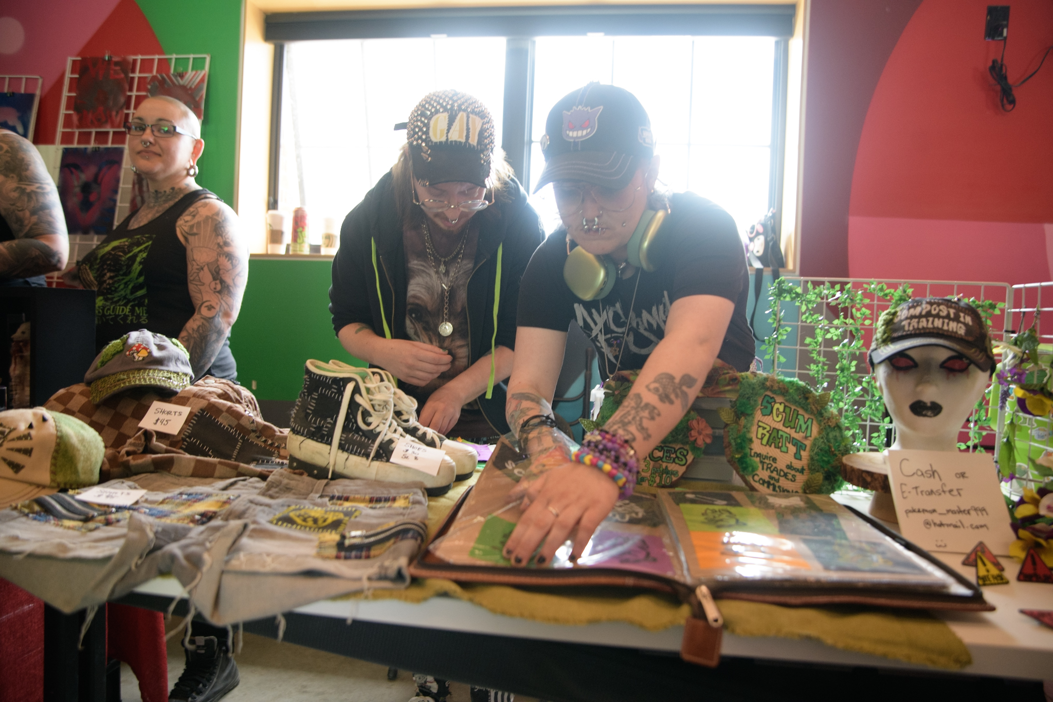 Two people stand behind their booth fiddling with an open photo of images laid out on their table. 