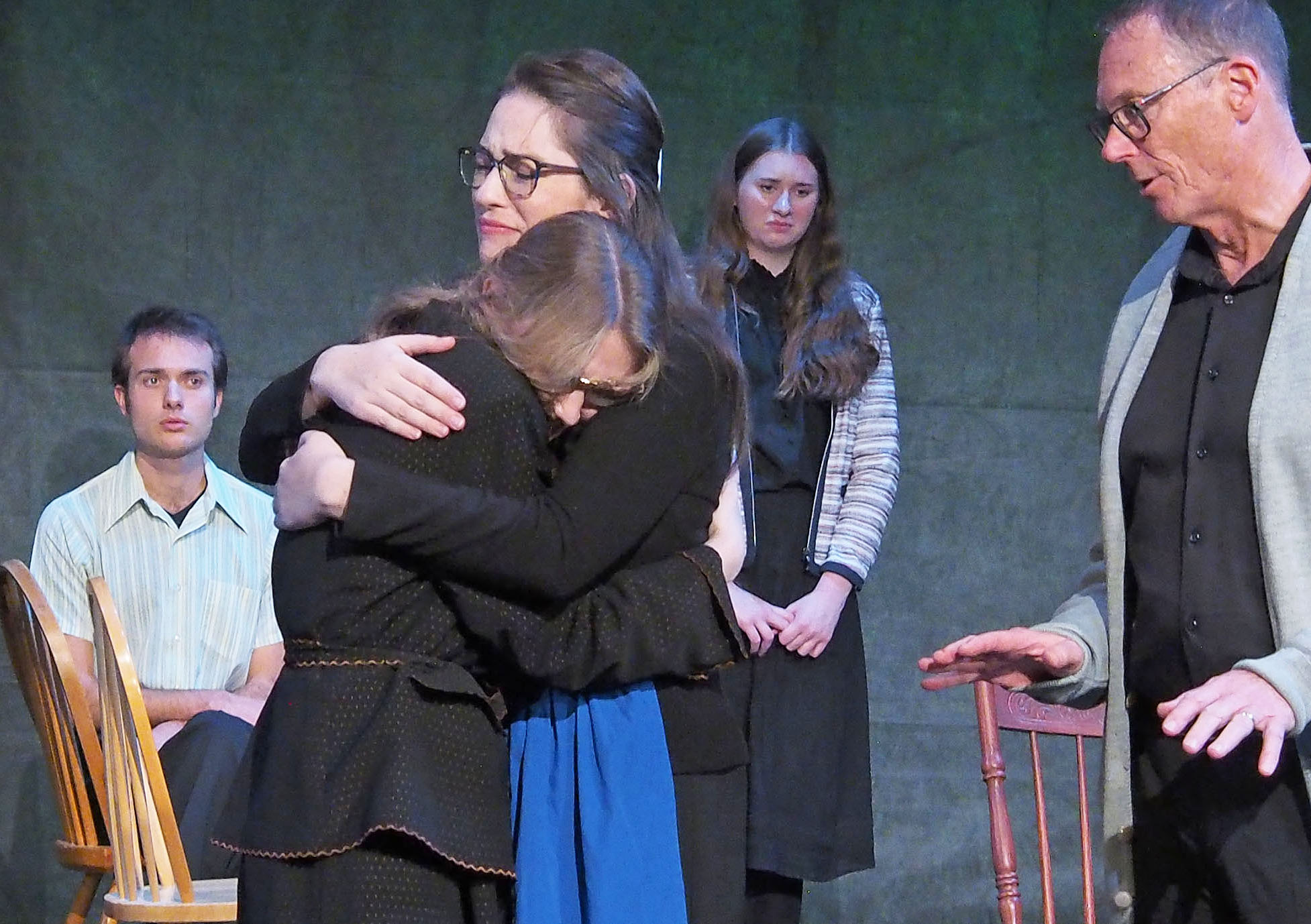 Two actors (Ashley Miller and Lauren Beazley) hug before a group. 